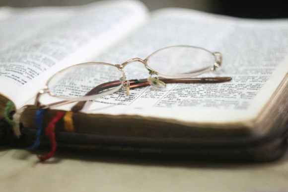 a picture showing an opened bible and a spectacle